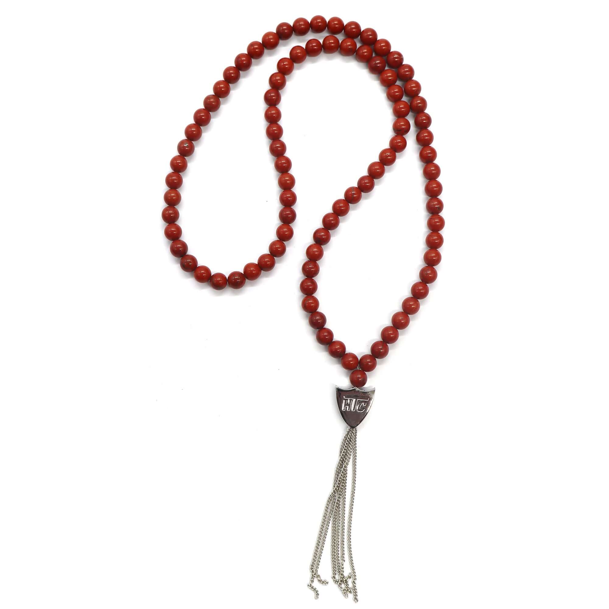htc los angeles MYSTERY SHIELD NECKLACE RED Red necklace featuring a blend of textile, glass, and metal materials, with a metal HTC logo detail. Hollywood Trading Company