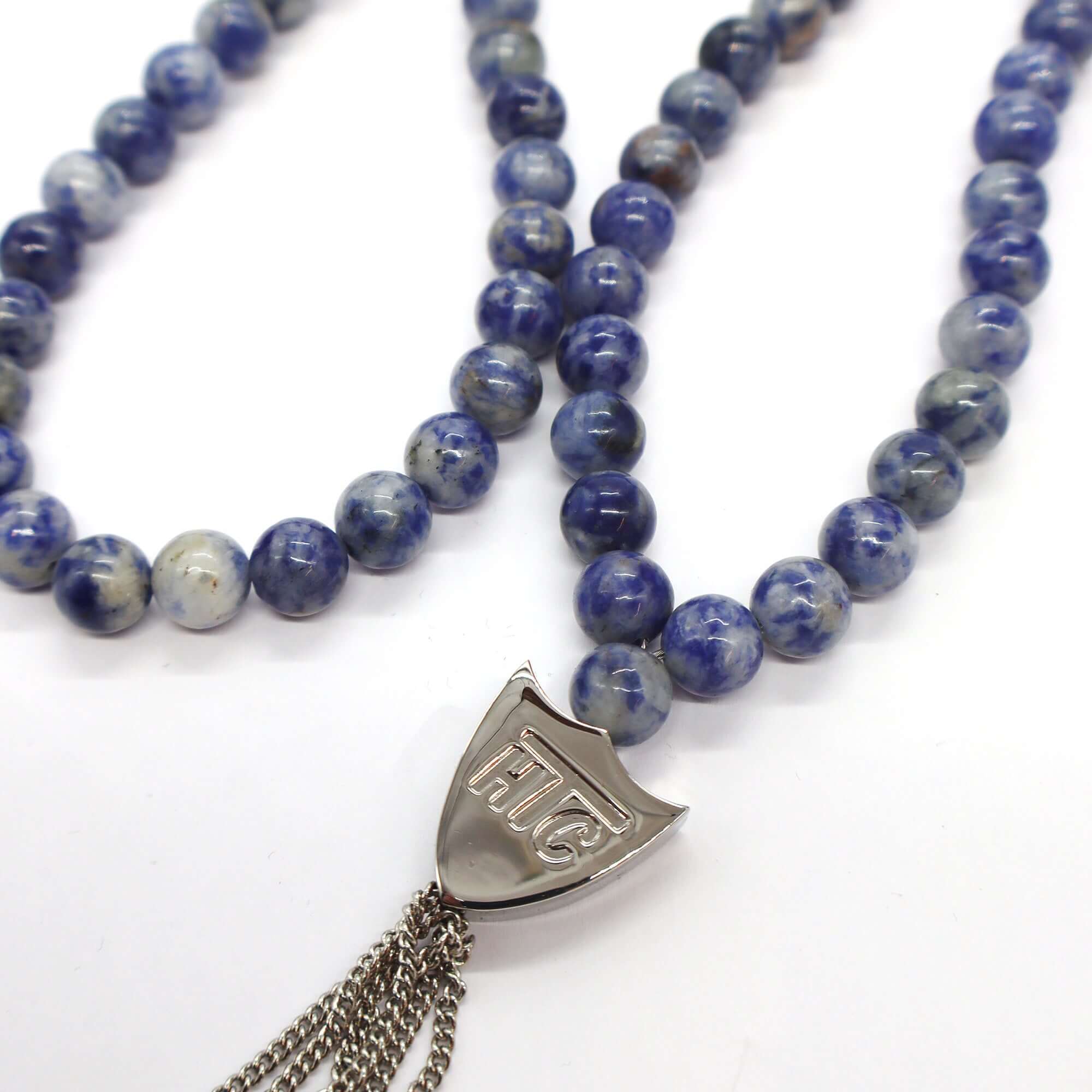 htc los angeles MYSTERY SHIELD NECKLACE SODALITE Sodalite necklace featuring a blend of textile, glass, and metal materials, with a metal HTC logo detail. Hollywood Trading Company