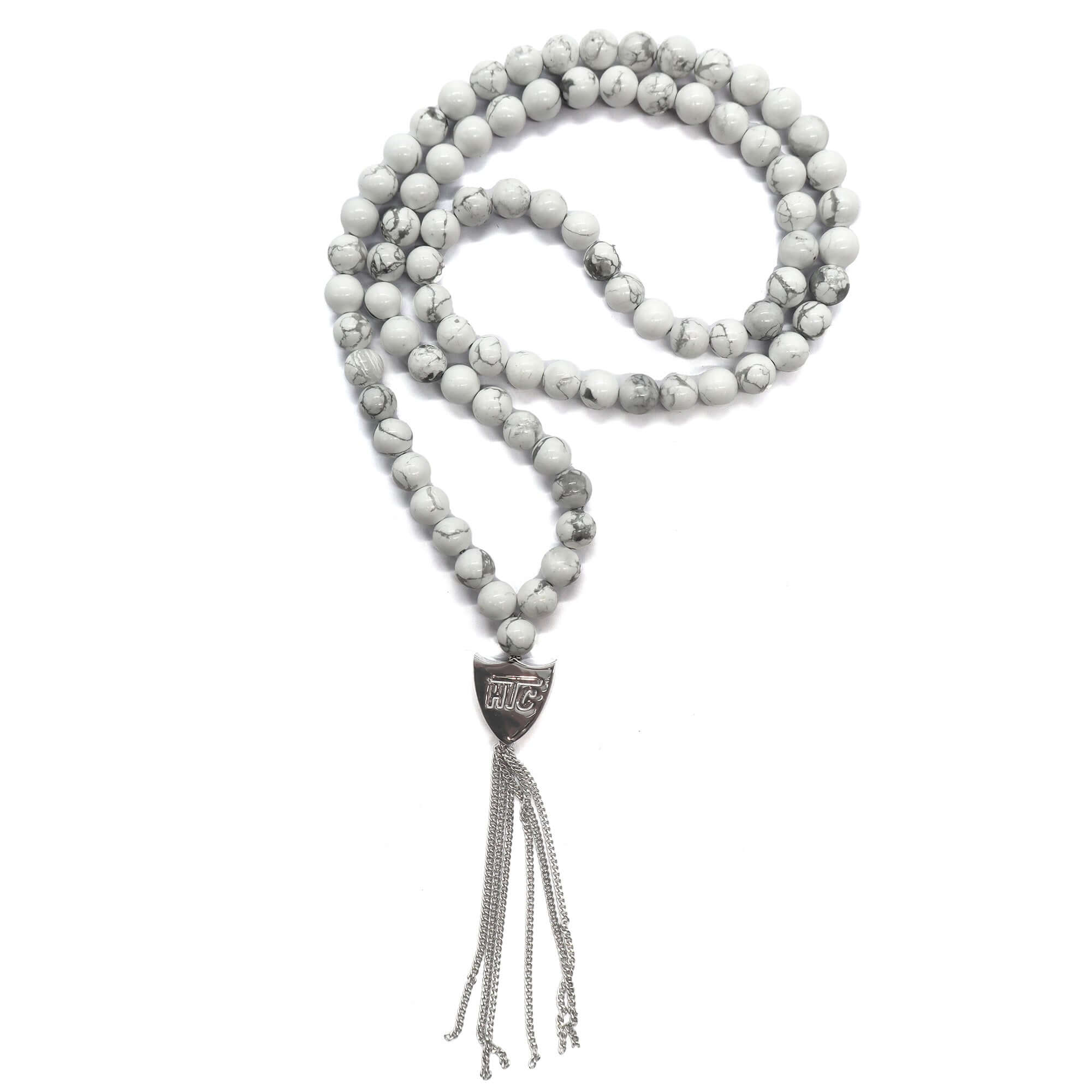 htc los angeles MYSTERY SHIELD NECKLACE WHITE White necklace featuring a blend of textile, glass, and metal materials, with a metal HTC logo detail. Hollywood Trading Company