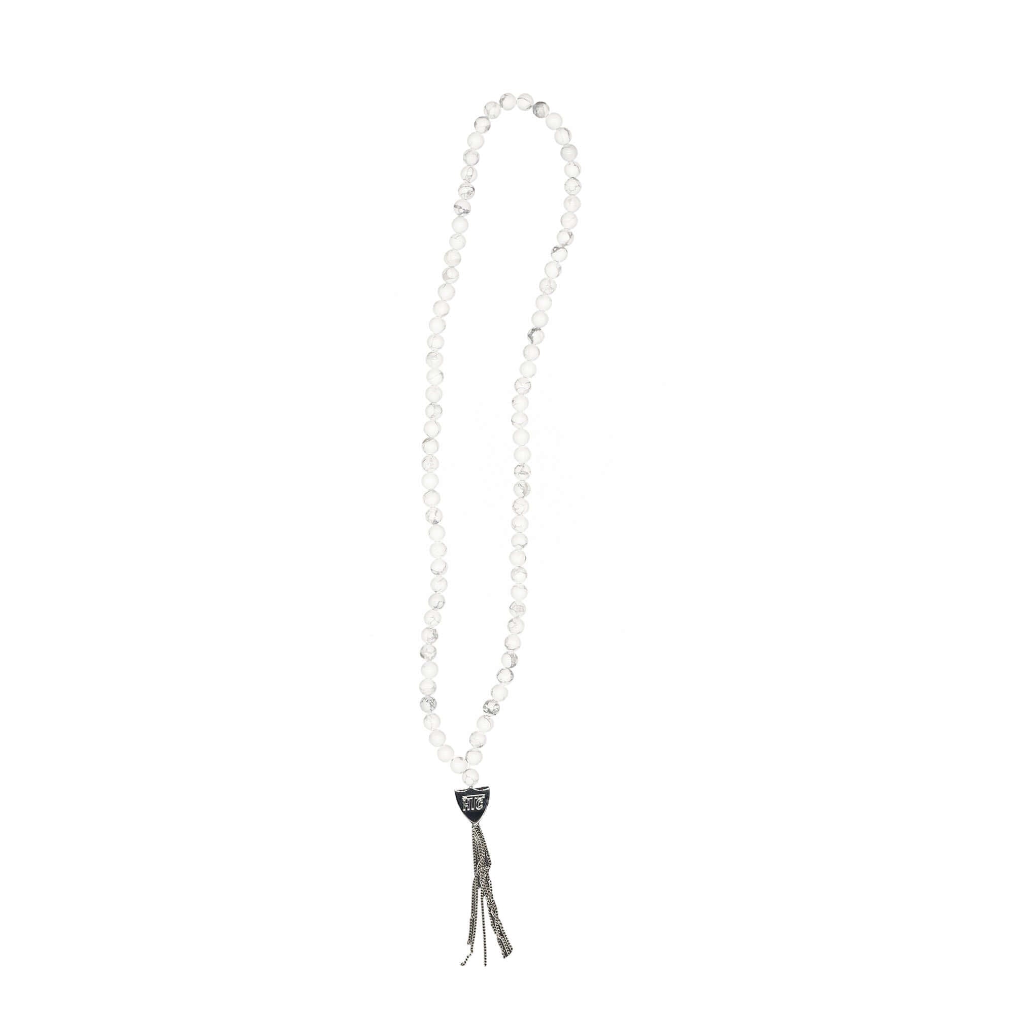 htc los angeles MYSTERY SHIELD NECKLACE WHITE White necklace featuring a blend of textile, glass, and metal materials, with a metal HTC logo detail. Hollywood Trading Company