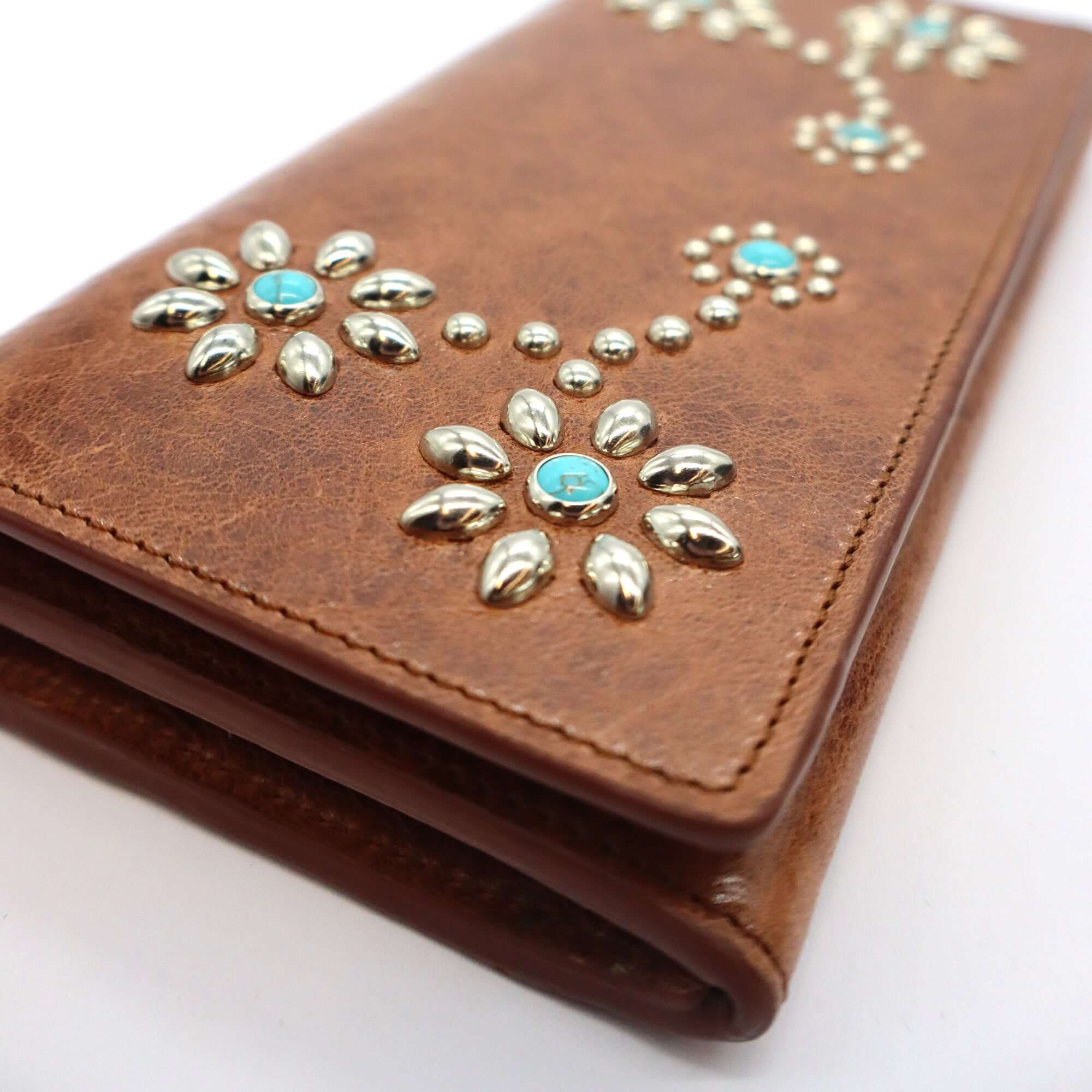 htc los angeles NANCY LONG WALLET Long wallet in Cognac, featuring a button closure. Designed with compartments for cards and coins, with flower studded details on the exterior. Crafted in Italy, 100% cow leather. Hollywood Trading Company